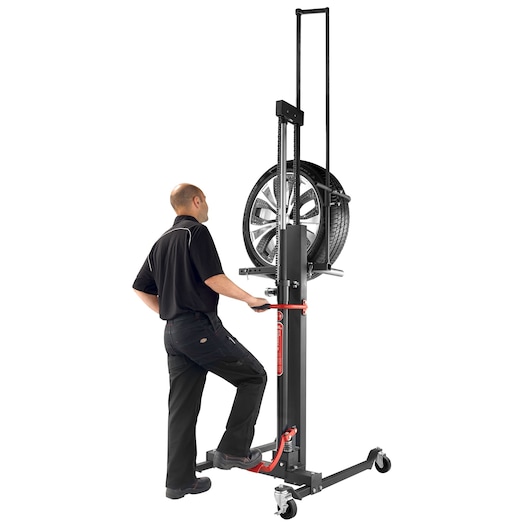 Facom DL_LR manual tire lift with black and red frame, operator handling automotive wheel, side angle, white background.