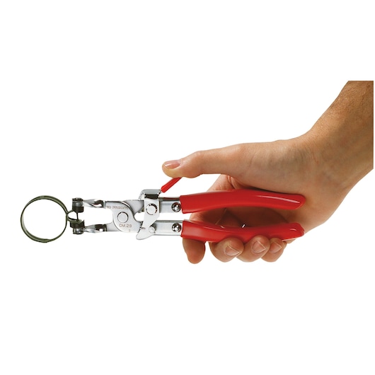 Facom DM27 snap ring pliers with red handles held in a right hand, side view.