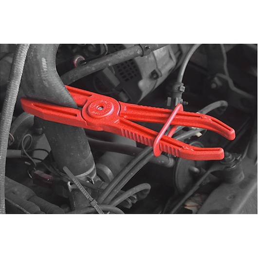Facom DM34 red hose clamp pliers in use on a car engine hose, automotive tool.