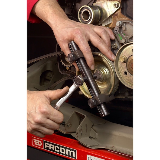Facom DM_50 automotive tool in use on engine pulley, close-up photography.