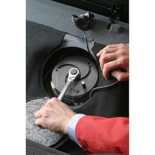 Photo of Facom DMJL ratchet tool in use on black automotive component, close-up angle.