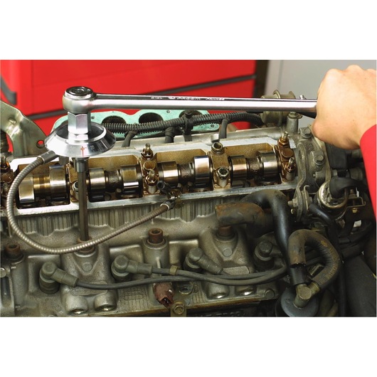 Facom DMP_360L torque wrench used on engine valve system, close-up photography of automotive maintenance.