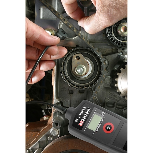 Facom DT_HERTZ belt tension tester measuring engine timing belt tension close-up.