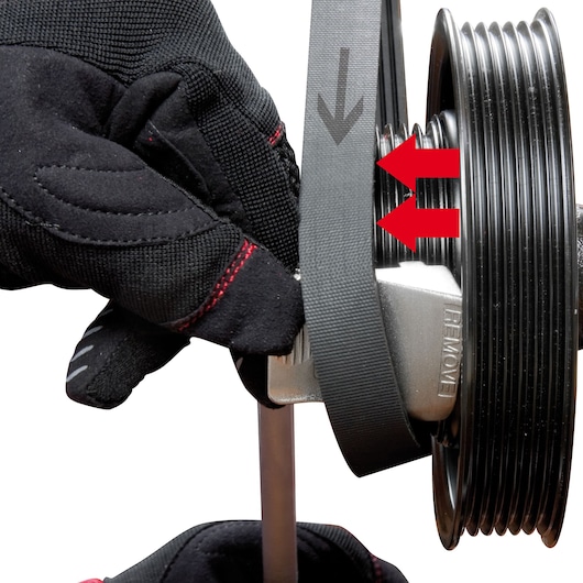 Facom DT_SFB tool in use for belt removal on pulley, close-up, black glove and directional arrows, white background