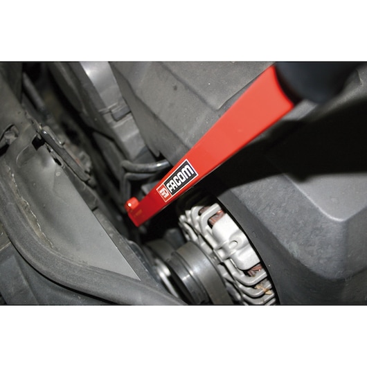 Facom DT_TWA red automotive tool in use near engine components, angled view.