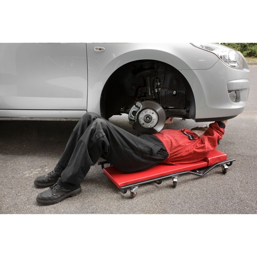 Facom DTS_1B photography of mechanic on red creeper working under car front wheel.