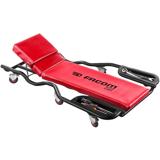 Facom DTS2B red mechanic's creeper with padded headrest, tool trays, black frame, and swivel casters, side angle.