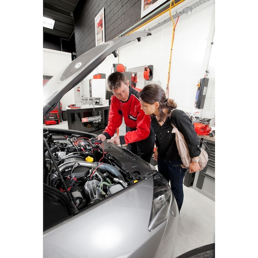 Photo of a Facom DX.10APB automotive diagnostic session in a workshop, mechanic using testing tools under car hood.