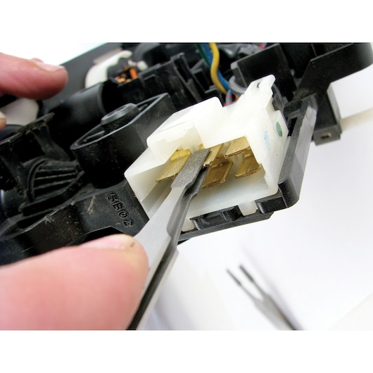 Facom DX145TCJ3 tweezers gripping connector pins, close-up on electronic component photography.