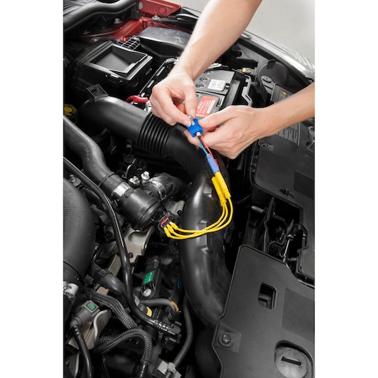 Facom DX_CONECT automotive connector tool in use with yellow cables near car engine, top view photography.