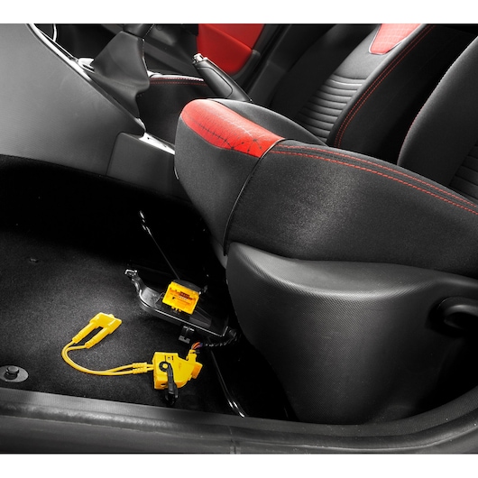 Facom DX_CONECT yellow automotive diagnostic connector on car floor near seat, angled view.