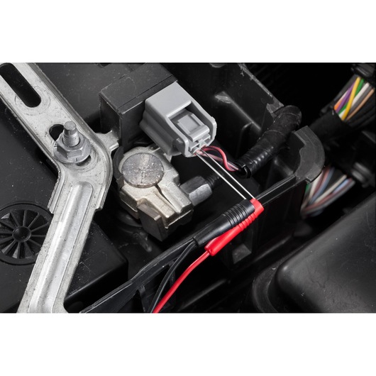 Facom DX.V12PB multimeter probes testing car electrical connector close-up.