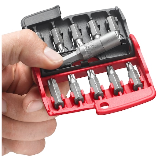 A close-up of a hand holding a red and black Facom bit set case, showing various metallic screwdriver bits organized in slots.