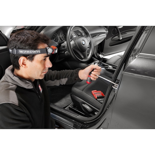 Facom E120PB screwdriver used on car door lock, red and black handle, seat kit visible inside.