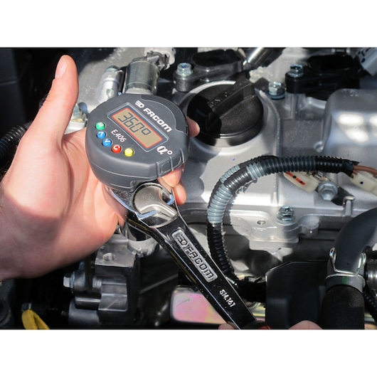 Facom E_406 digital torque angle wrench used on engine, close-up photography.