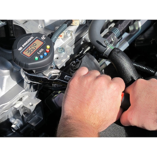Facom E_406 digital torque wrench in use on engine part, close-up showing display screen and control buttons.