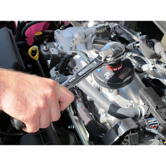 Facom E506-135S ratchet wrench used on engine components, close-up photography.