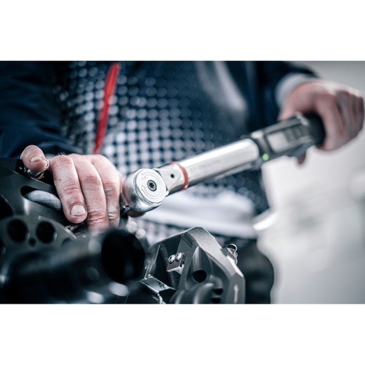 Facom E_516ST-135PB torque wrench in use, close-up showing hand operation on machinery.