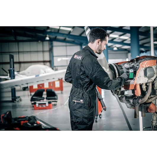 Facom E_516ST-30PB black coverall worn by mechanic working on aircraft engine in hangar.