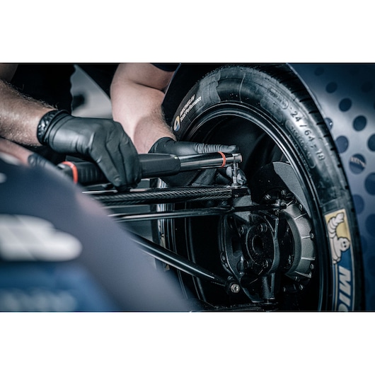Facom E_516ST-30PB torque tool used on race car wheel, mechanic wearing black gloves, close-up photography