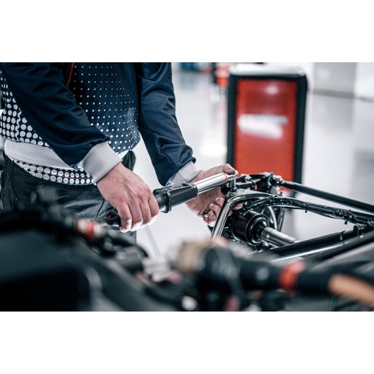 Facom E_516ST-30PB torque wrench used by technician on vehicle part, garage setting.