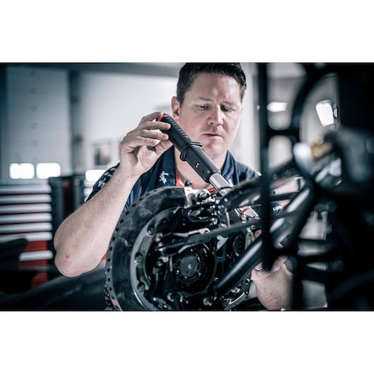 Facom E_516ST-30PB photography of technician using hand tool on motorcycle wheel in workshop.