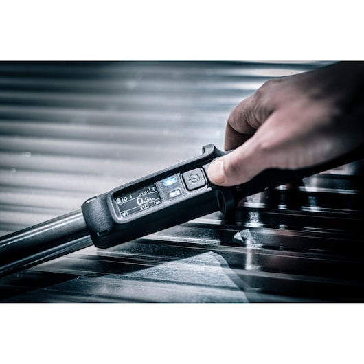 Facom E_516ST-30PB digital torque wrench hand-held, close-up on metal surface.
