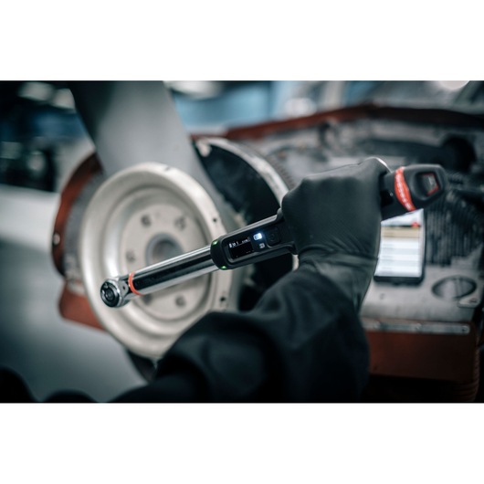Facom E_516ST-30PB electronic torque wrench in use near a car brake disc, close-up photography.