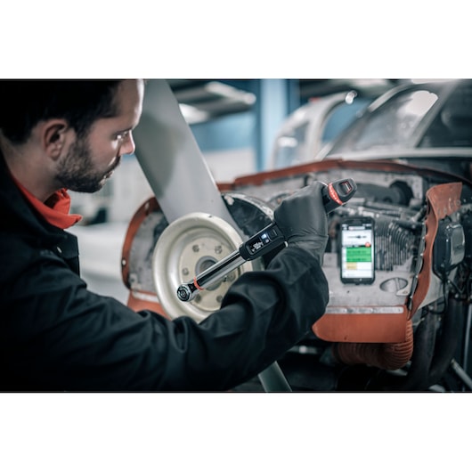 Photo of Facom E_516ST-30PB digital torque wrench used on an aircraft engine in a workshop.