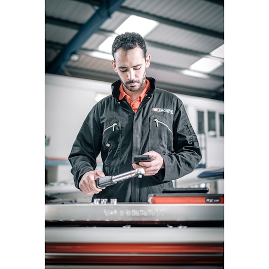 Facom E_516ST-340PB photography of technician in black Facom jacket using a torque wrench in workshop.