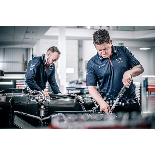 Facom E_516ST-340PB torque wrench used by technicians working on an automotive engine in a workshop.