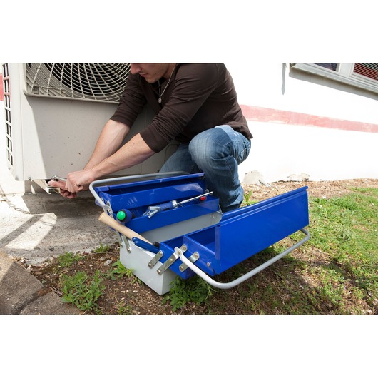 Facom E010201 metal tool box with blue compartments open beside technician working outdoors.