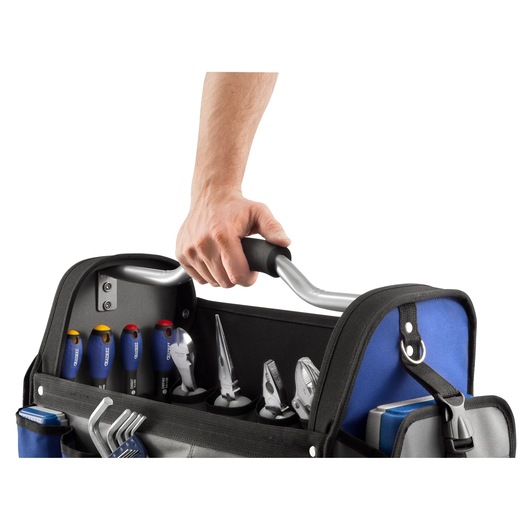 A close-up of a person's hand holding the handle of a blue and black tool bag filled with various hand tools, including screwdrivers, pliers, and hex keys.