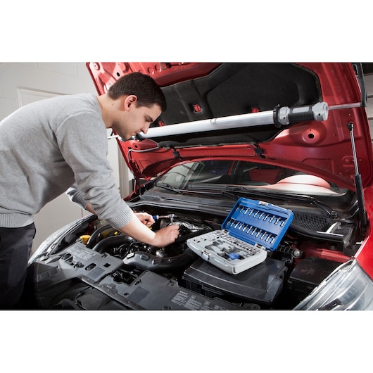 Facom E030702 tool set open on car engine, mechanic using tools for automotive repair, photo of workspace.