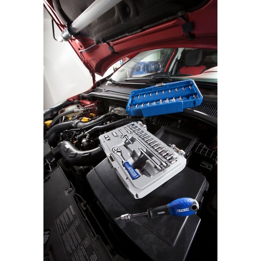Facom E030702 socket and bit set with blue handles on car engine during maintenance, photography angle.