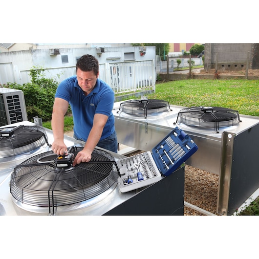 Facom E034805 socket set photography with technician using tools on industrial HVAC units outdoors.