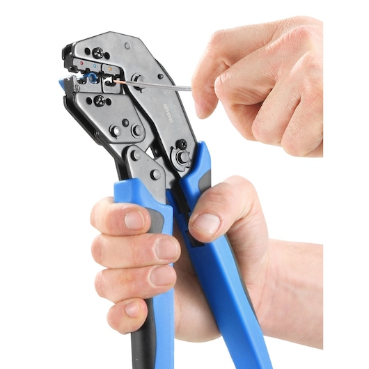A pair of hands using a blue-handled crimping tool to work with a wire.
