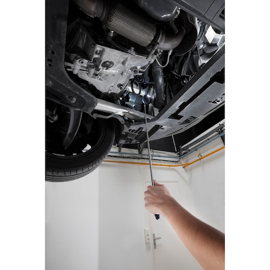 Facom E051401 photography of mechanic using tool under a car in a garage.