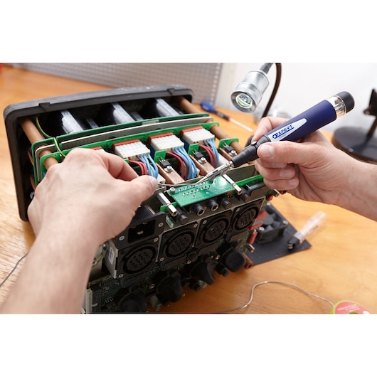 Facom E090501 electronics repair with soldering iron on circuit board, close-up photography.