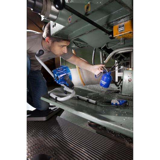 Facom E090701 industrial fluid dispenser in use near factory machinery, blue and grey components visible.