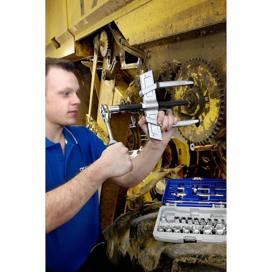Facom E096002 socket set being used by worker on industrial machinery, blue and grey cases open nearby.