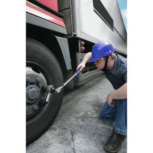 Facom torque wrench E100107 used by worker with blue helmet on truck wheel outdoors.