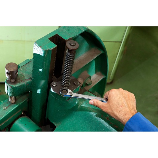 Facom E111107 ratcheting wrench used on green machinery in workshop setting.