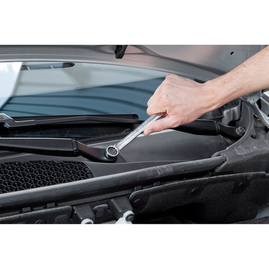 Facom E113240 ratcheting wrench used on car windshield wiper assembly, close-up photography.