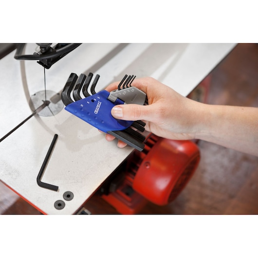 Facom E113929 hex key set in blue and grey holder, held by hand near metalwork machinery.