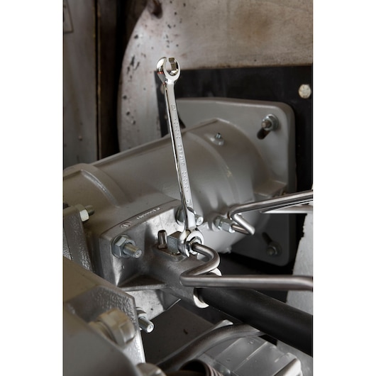 Photo of Facom E117388 combination wrench in use on a metal machine part.