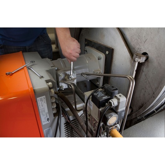 Facom E117395 wrench being used to tighten bolts on industrial machinery, close-up view.
