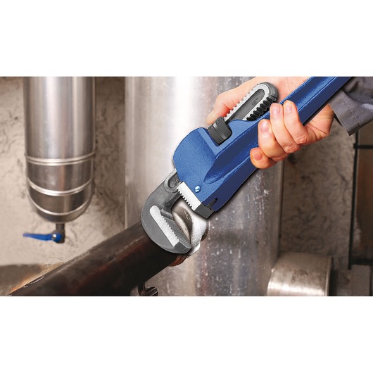 Facom E117822 pipe wrench in use gripping a metal pipe, close-up photo showing tool details.