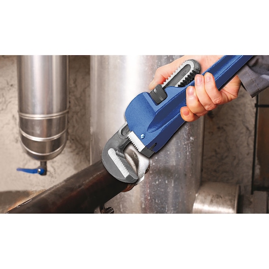 Facom pipe wrench E117823 used by hand to grip a metal pipe, industrial background.