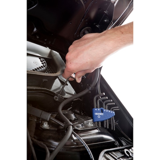 Facom E121102 hex key set used for automotive repair, close-up of hand working inside engine bay.